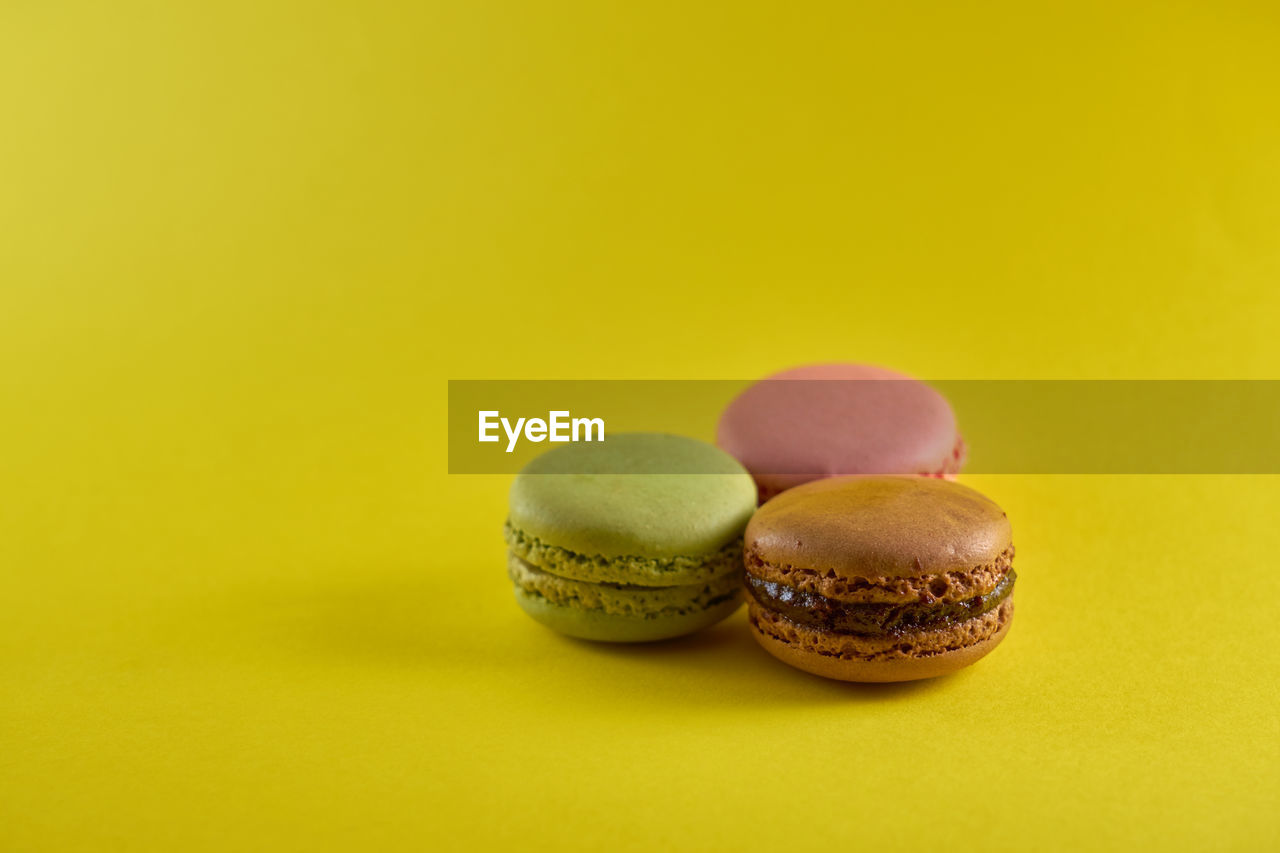 Cake macaron on yellow background flavor almond cookies pastel colors and space for text.