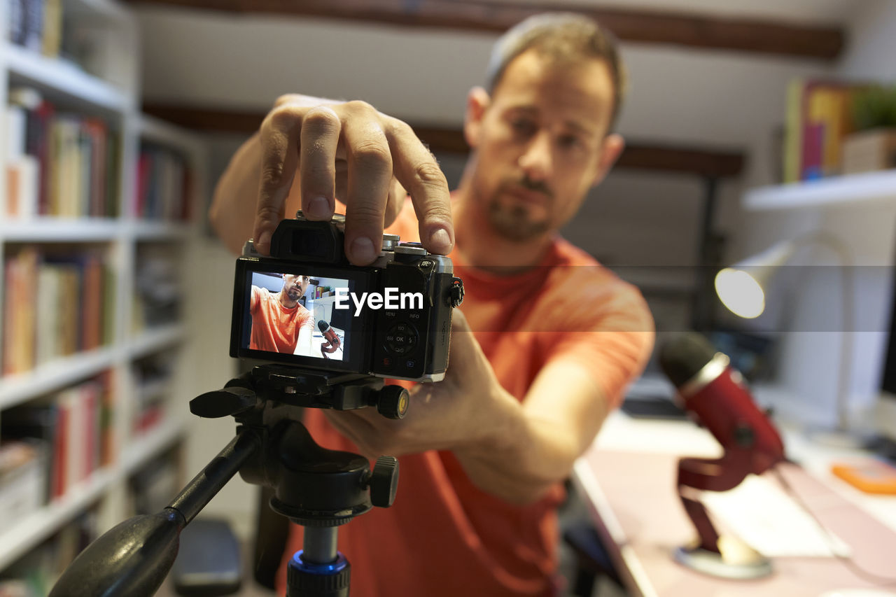 Mid adult man adjusting camera for recording video tutorial