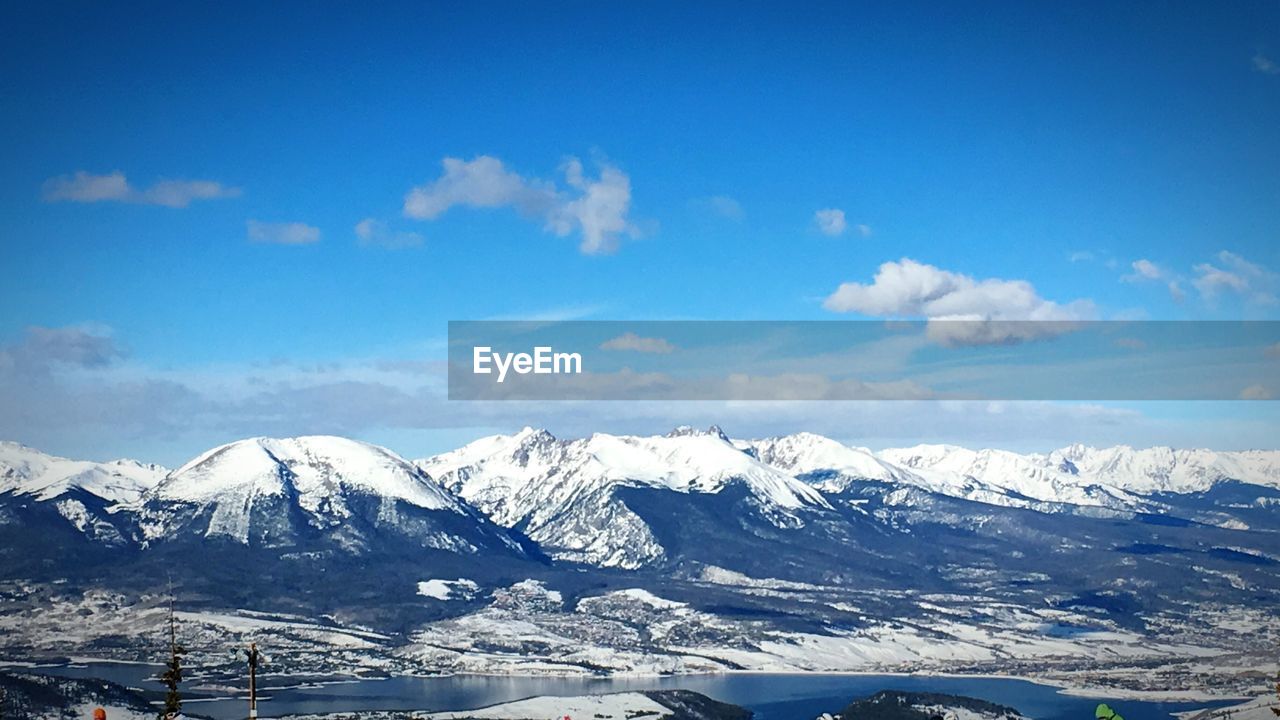 Scenic view of snow covered mountains against blue sky