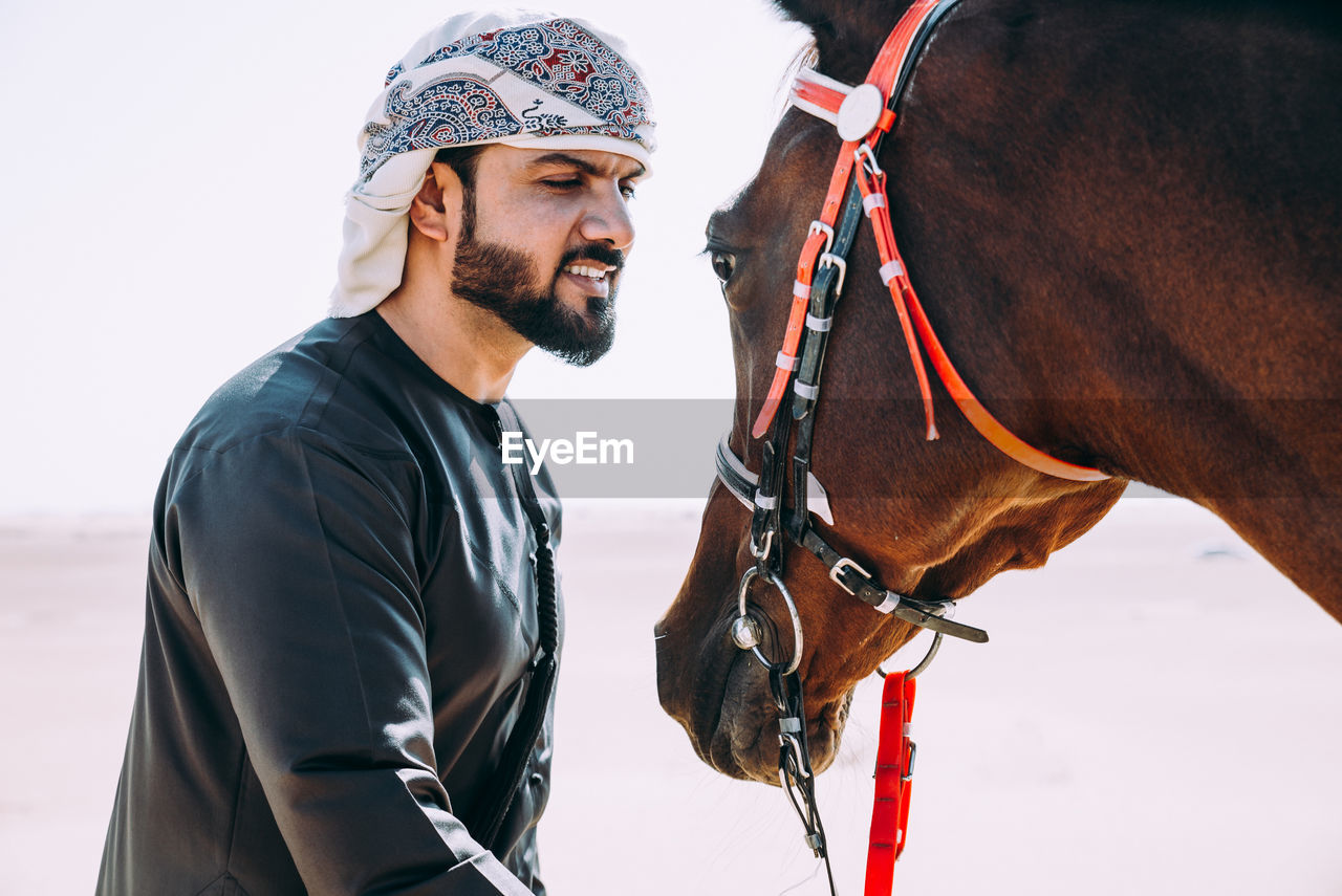 Man looking at horse while standing in desert