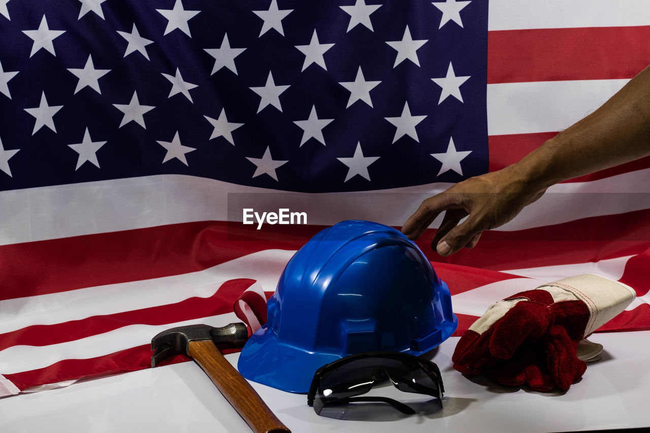 Cropped hand touching hardhat against american flag