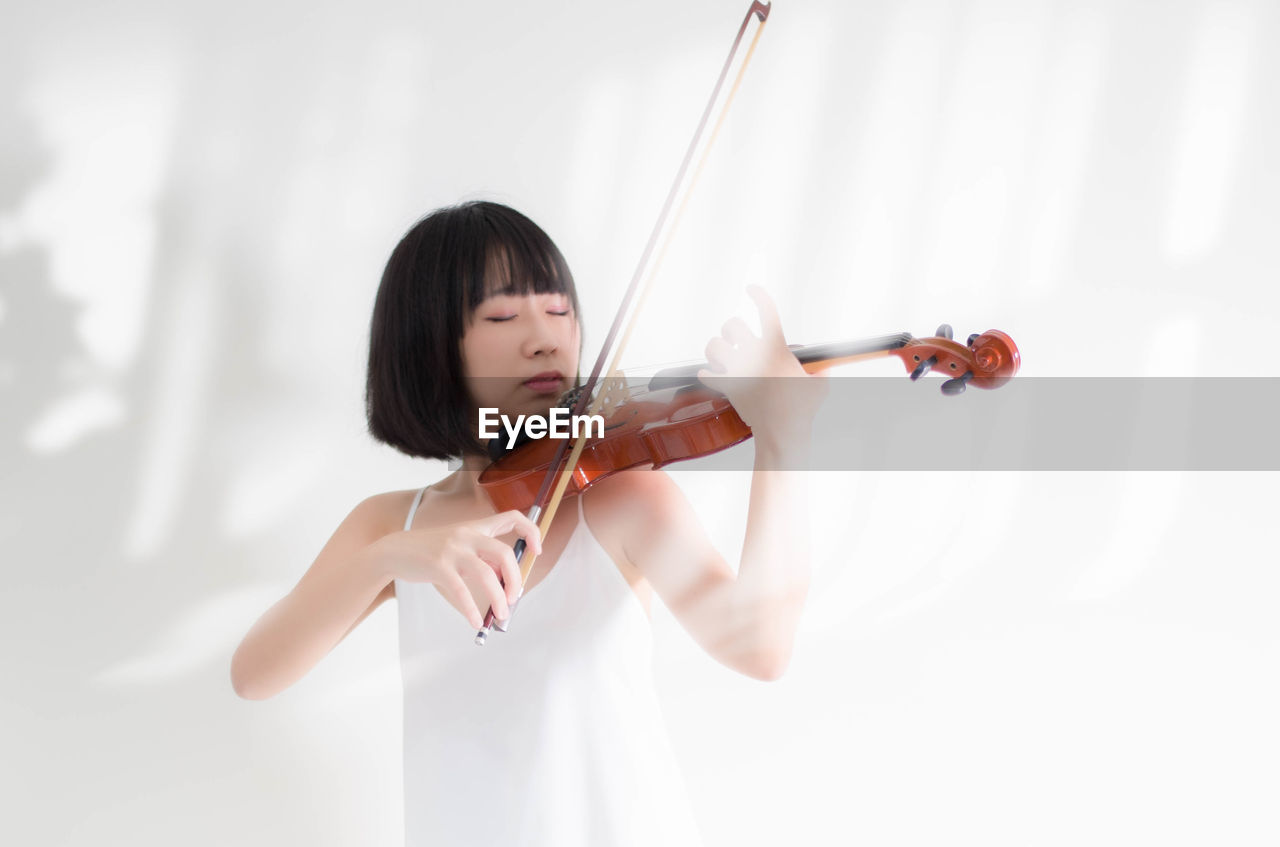 Young woman playing violin at home