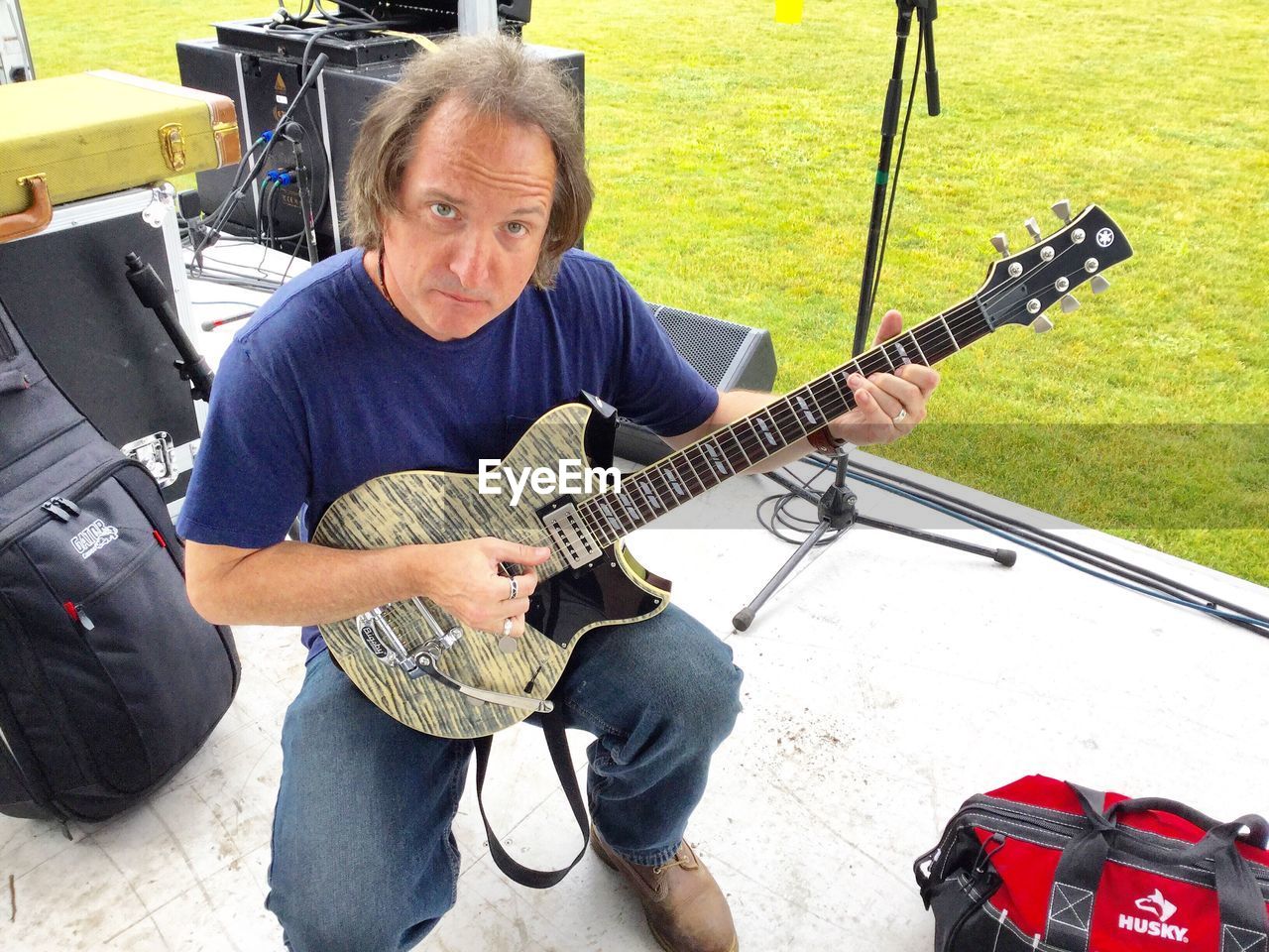 Portrait of man playing guitar while kneeling on stage