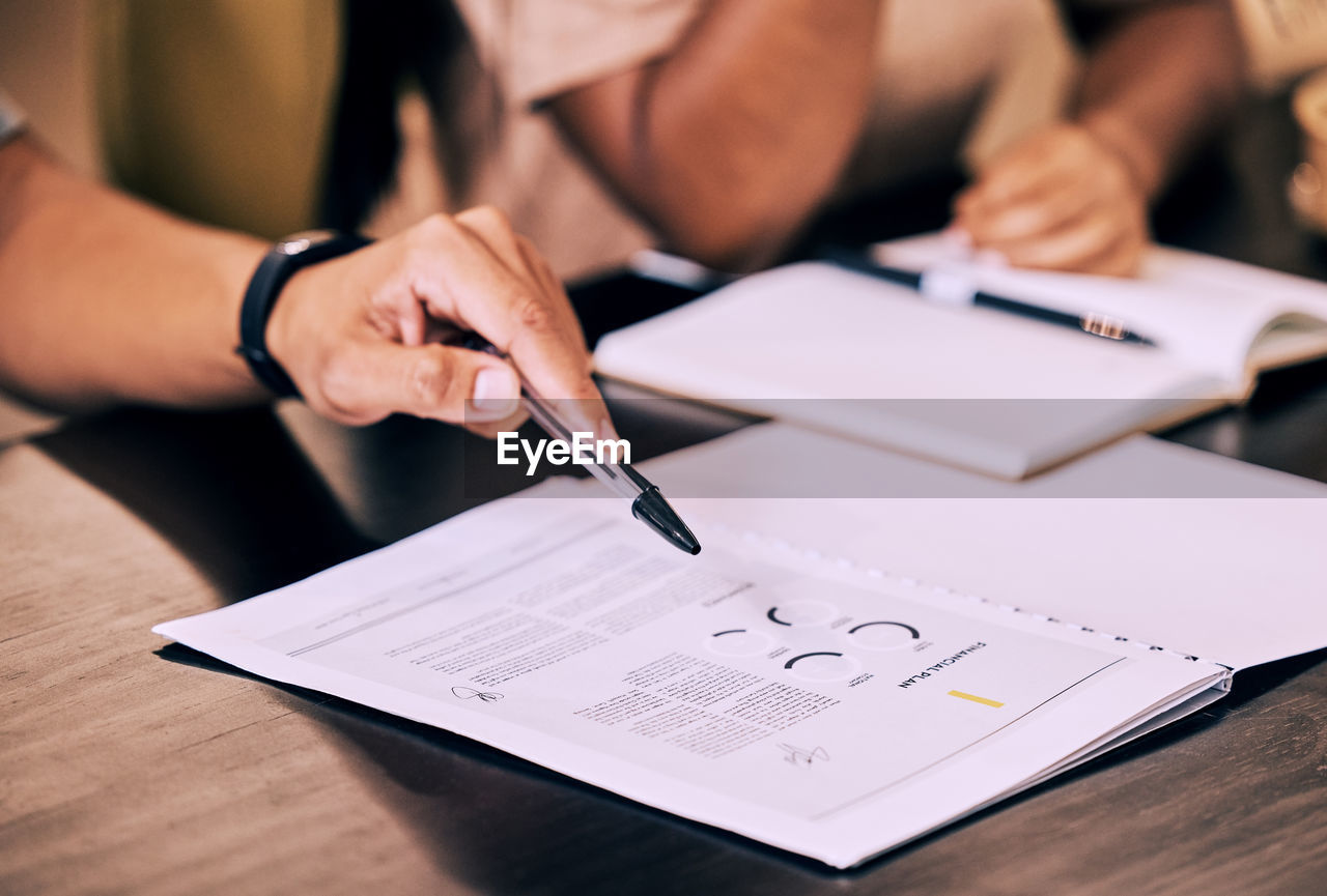 midsection of woman writing in book at table