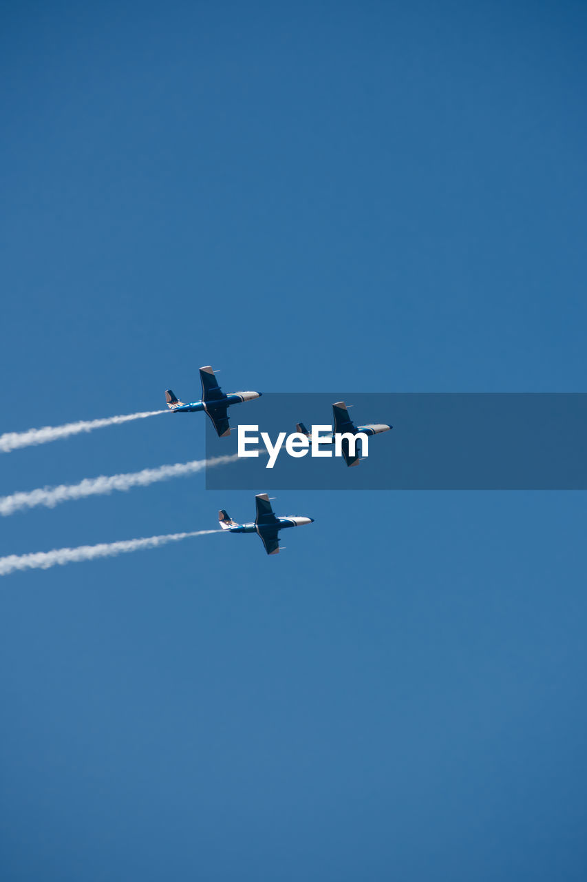 Low angle view of airplane flying against clear blue sky