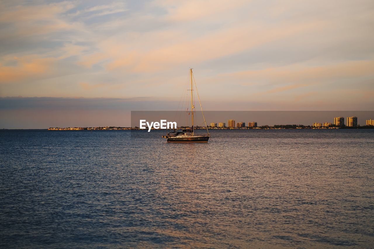 Sailboat sailing on sea against sky during sunset