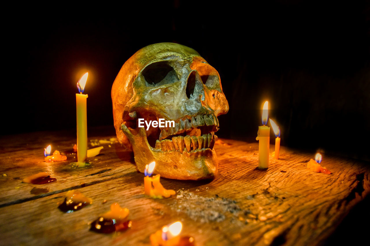 Close-up of lit candles around human skull on table