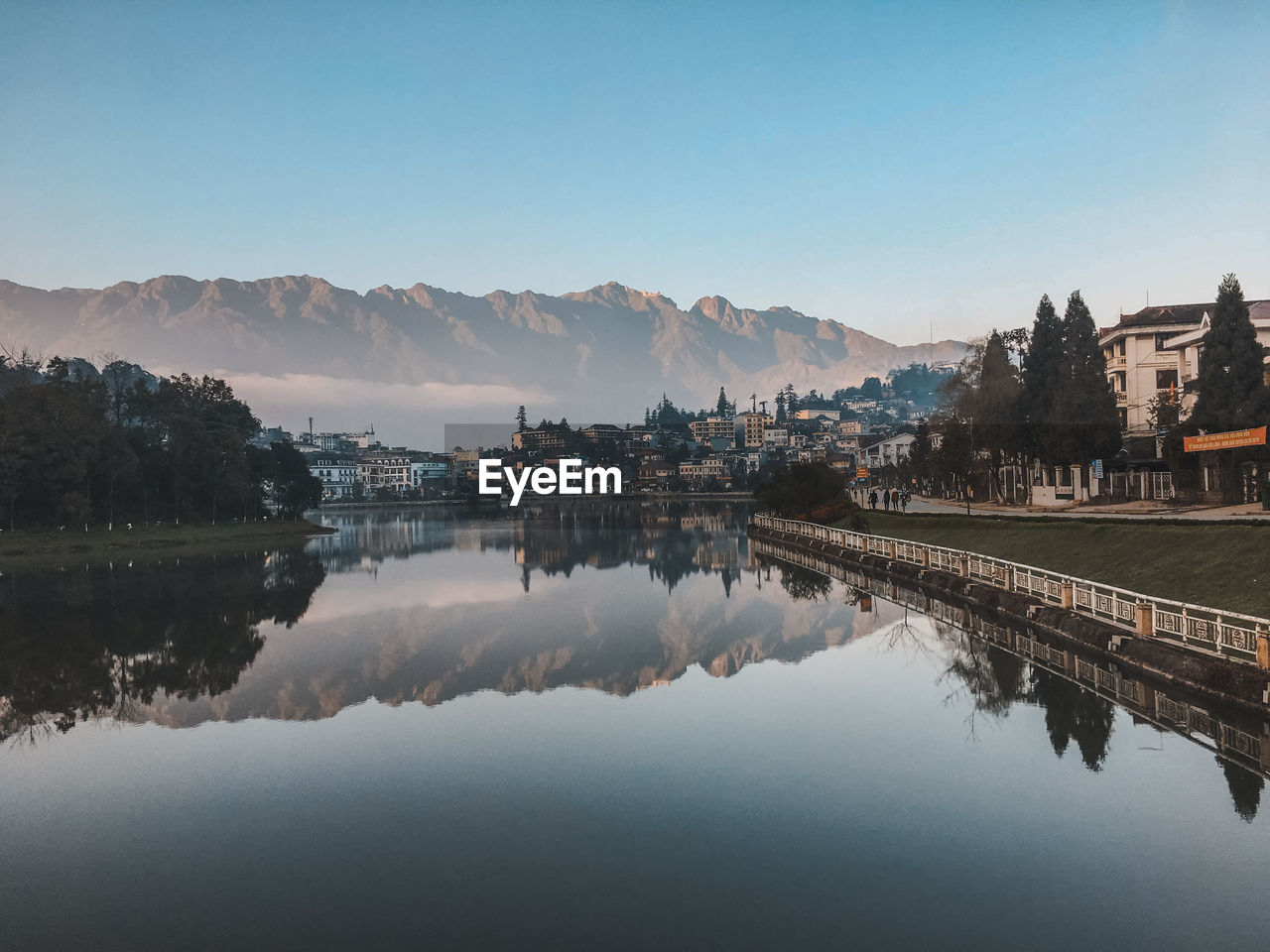 Reflection of buildings in lake against clear sky