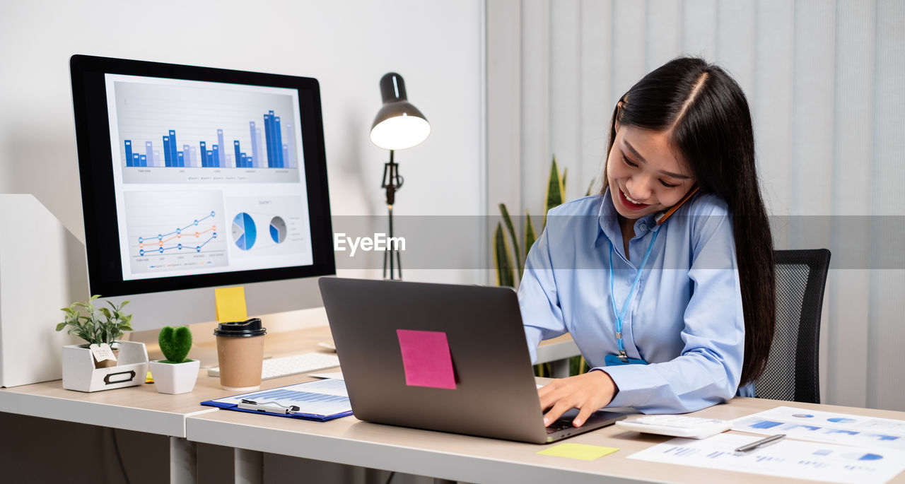 WOMAN USING LAPTOP ON TABLE AT HOME