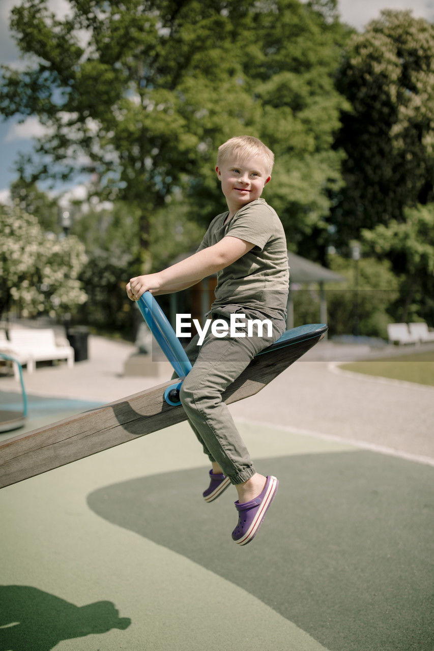 Full length side view of boy with down syndrome enjoying seesaw at park