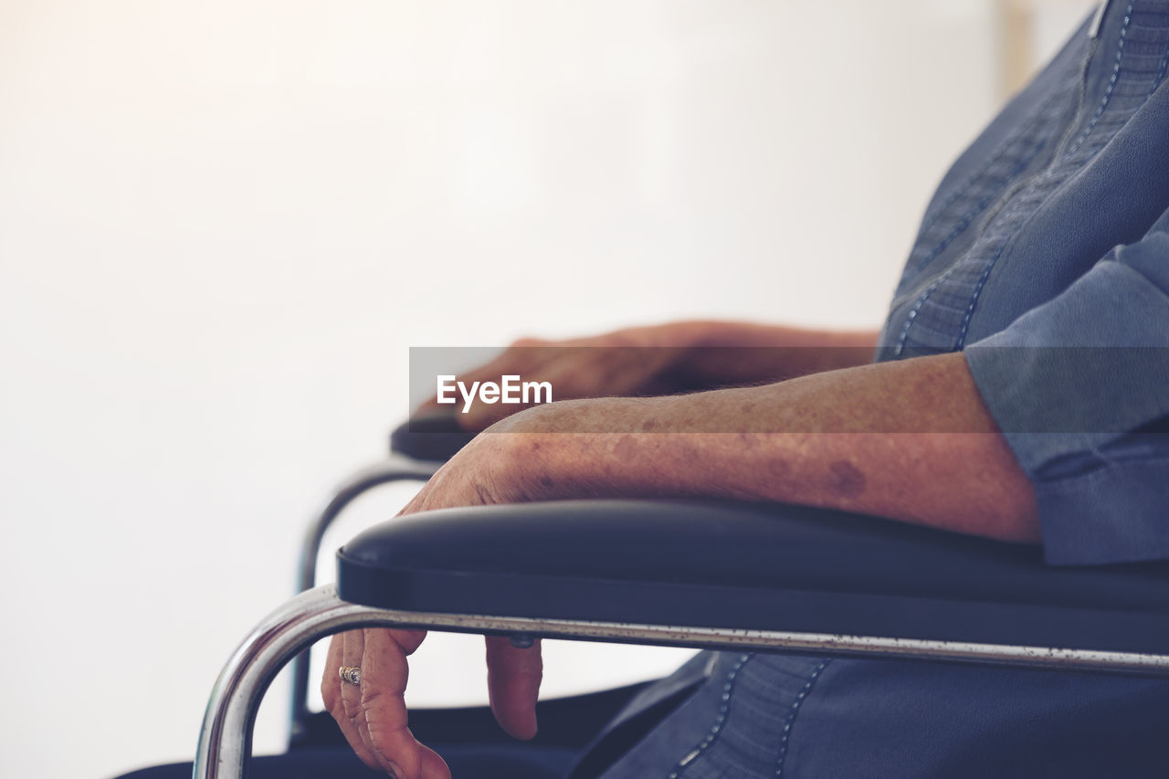 Side view of senior woman sitting on wheelchair by window