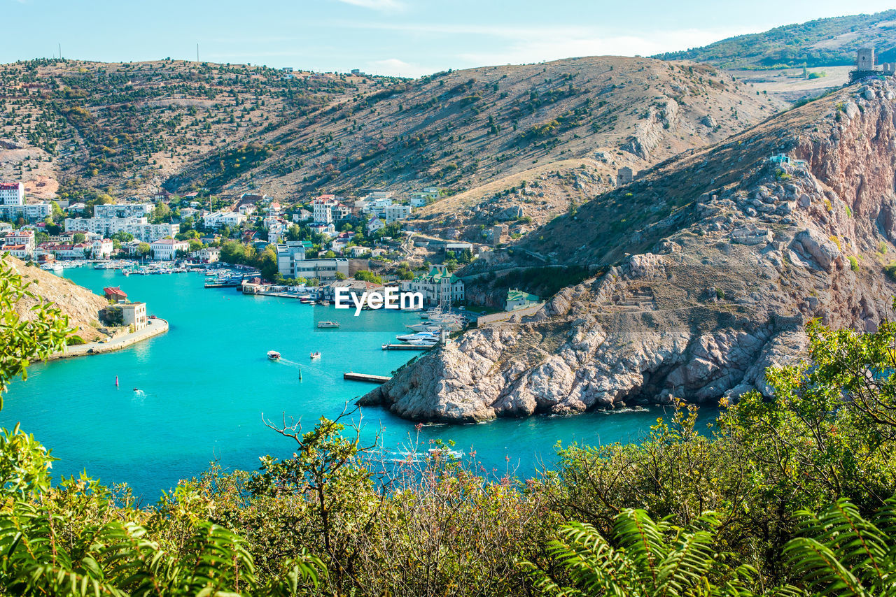 HIGH ANGLE VIEW OF TREES AND SEA AGAINST MOUNTAINS