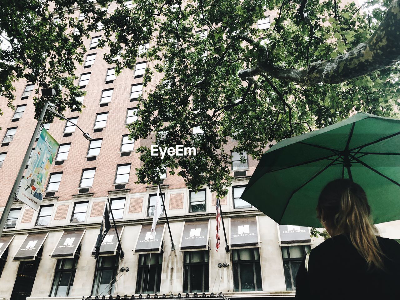 REAR VIEW OF WOMAN ON BUILDING DURING RAIN