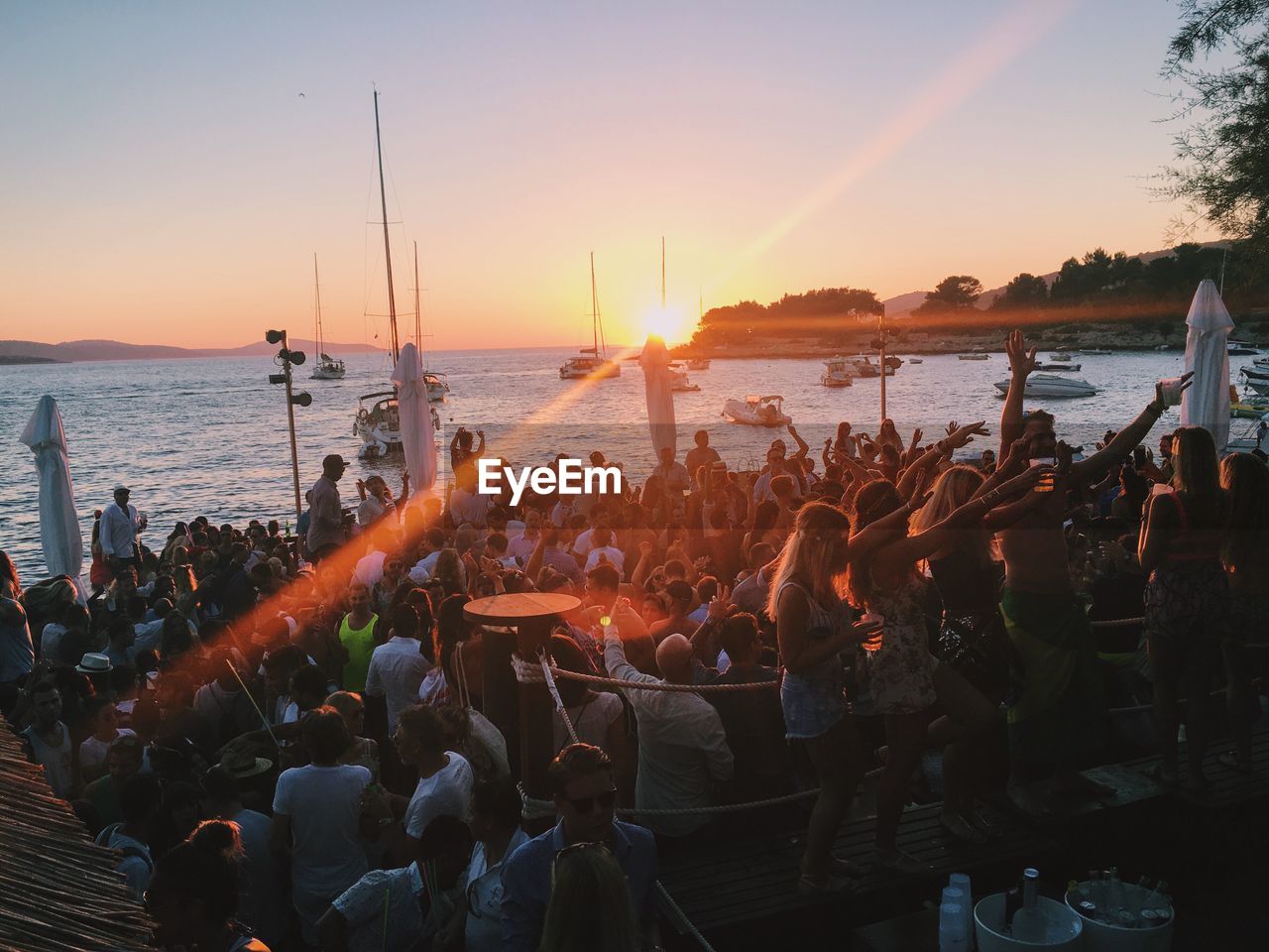People enjoying at party by sea during sunset