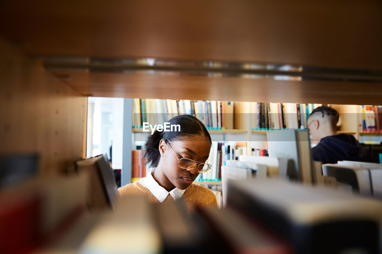 Male and female students reading books in university library