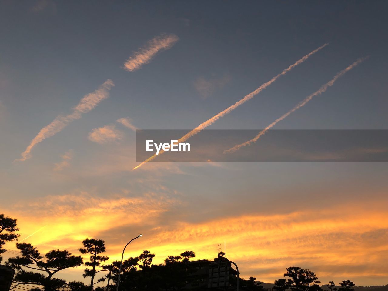 LOW ANGLE VIEW OF VAPOR TRAILS IN SKY DURING SUNSET