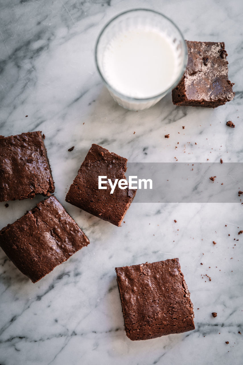 Top view of tasty chocolate brownie slices on marble table near glass of milk