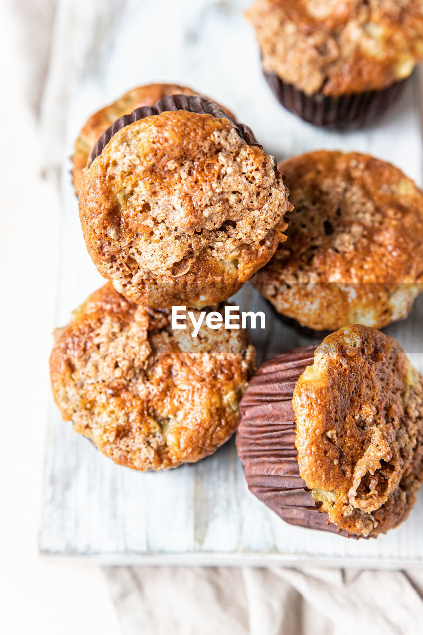 Tasty breakfast muffins with oat crumbs topping on cutting board.