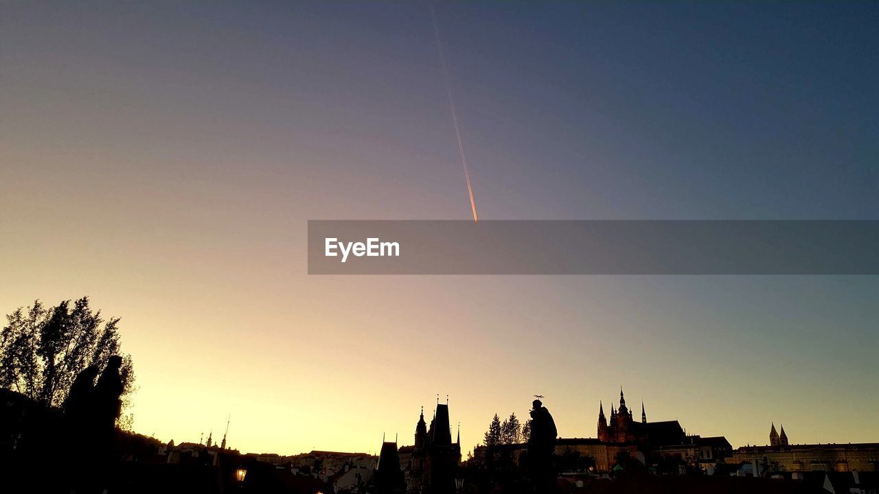 SILHOUETTE VAPOR TRAILS IN SKY