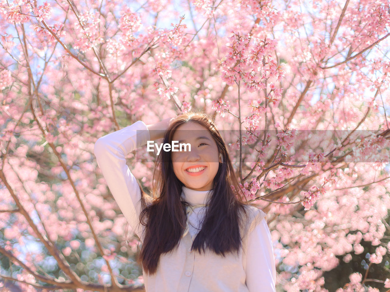 PORTRAIT OF BEAUTIFUL YOUNG WOMAN STANDING BY CHERRY BLOSSOM