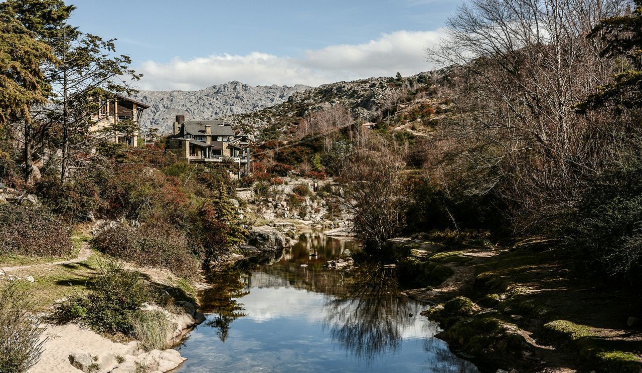 Houses by river and mountains against sky