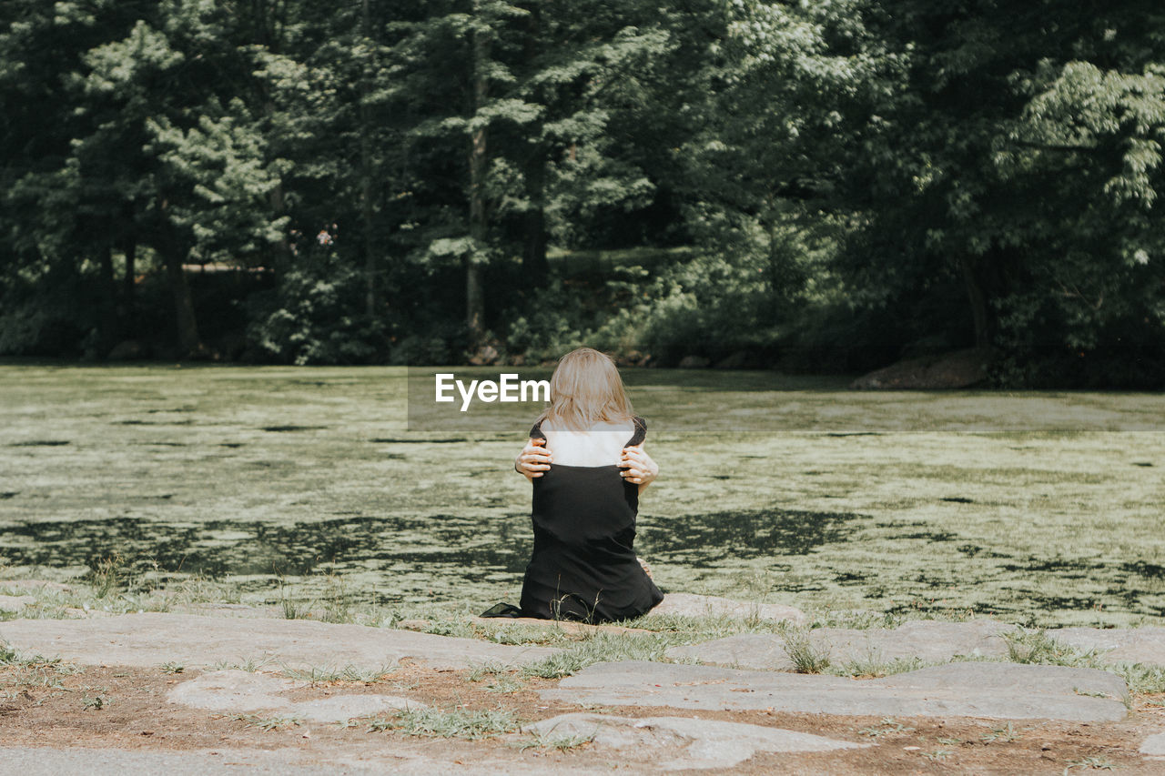 Rear view of woman sitting on swamp