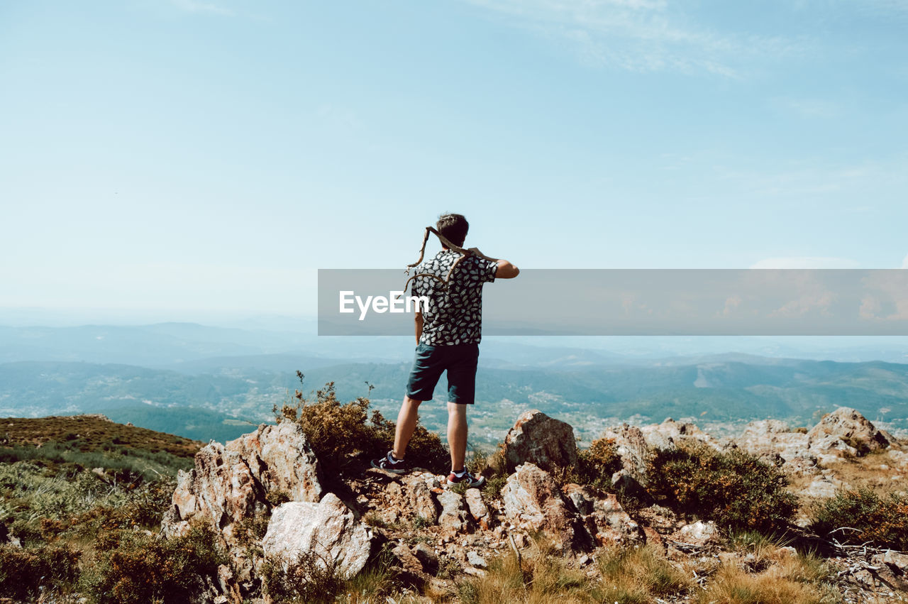 Rear view of man standing on rock against mountain