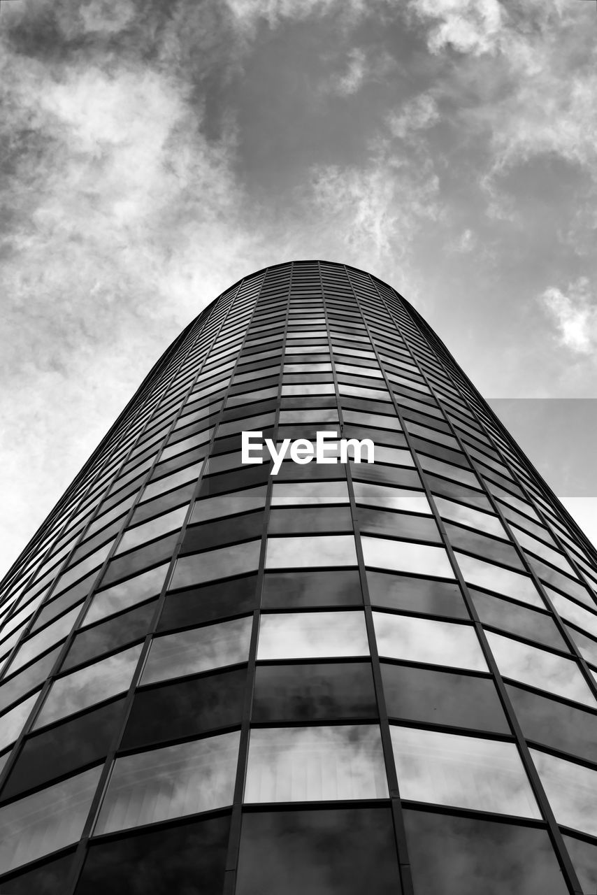 LOW ANGLE VIEW OF GLASS BUILDING AGAINST CLOUDY SKY