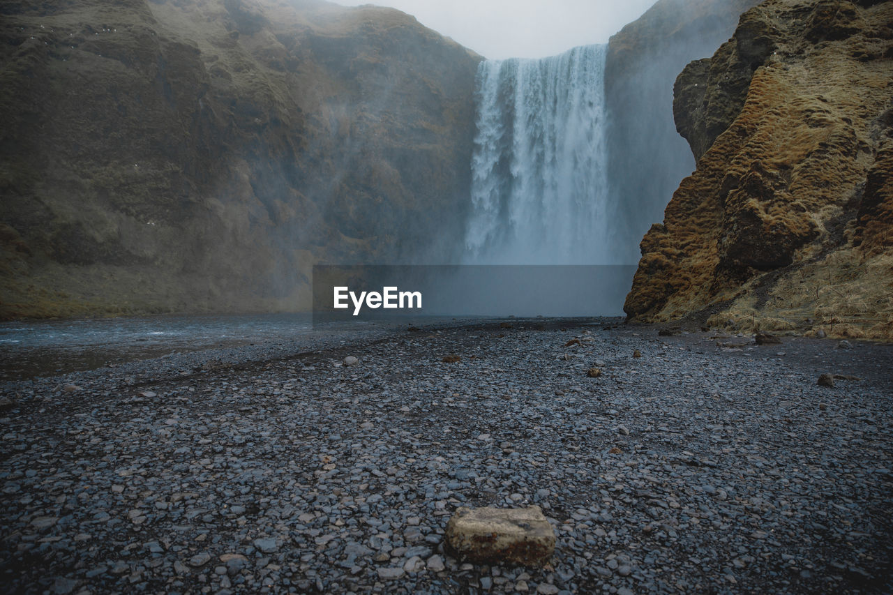 SCENIC VIEW OF WATERFALL BY ROCK FORMATION