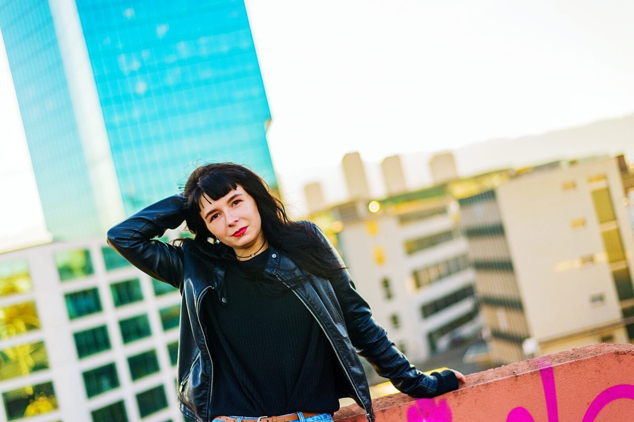 Portrait of fashionable young woman standing against buildings in city