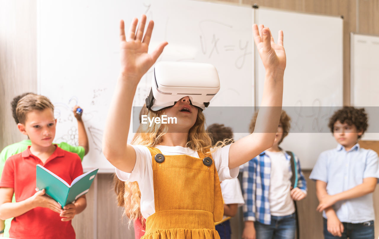 Cute girl using virtual reality simulator at classroom