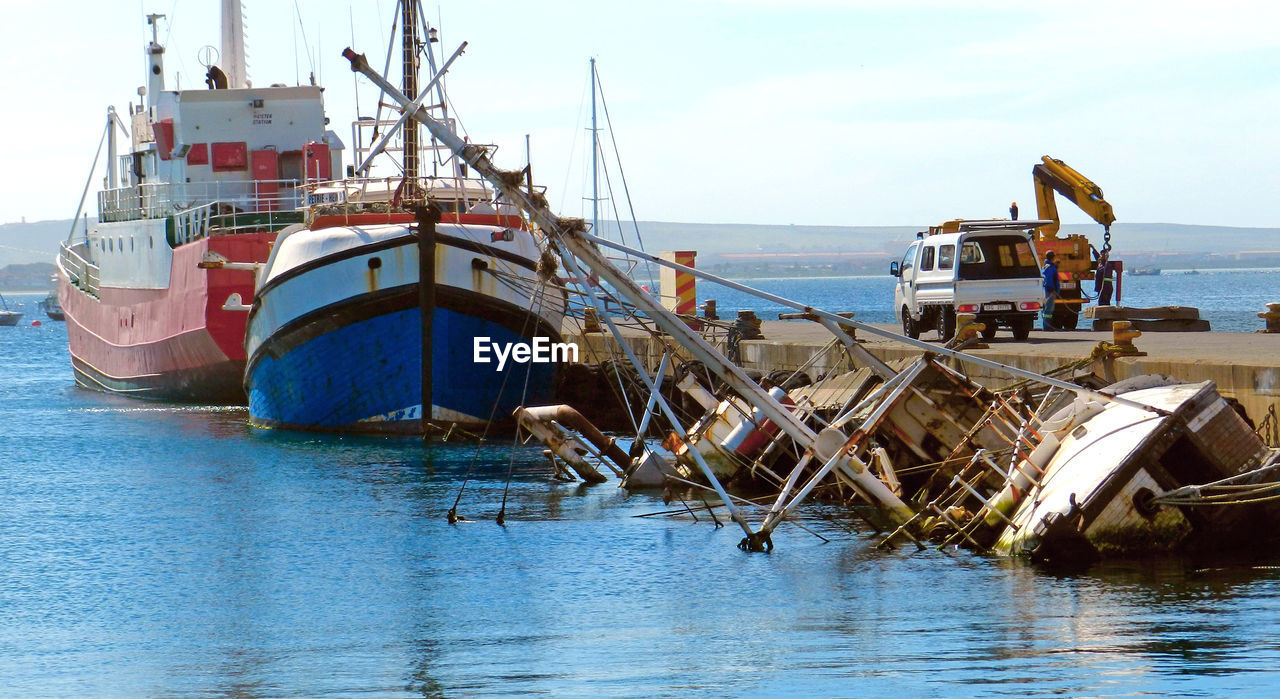 FISHING BOAT MOORED AT SEA AGAINST SKY