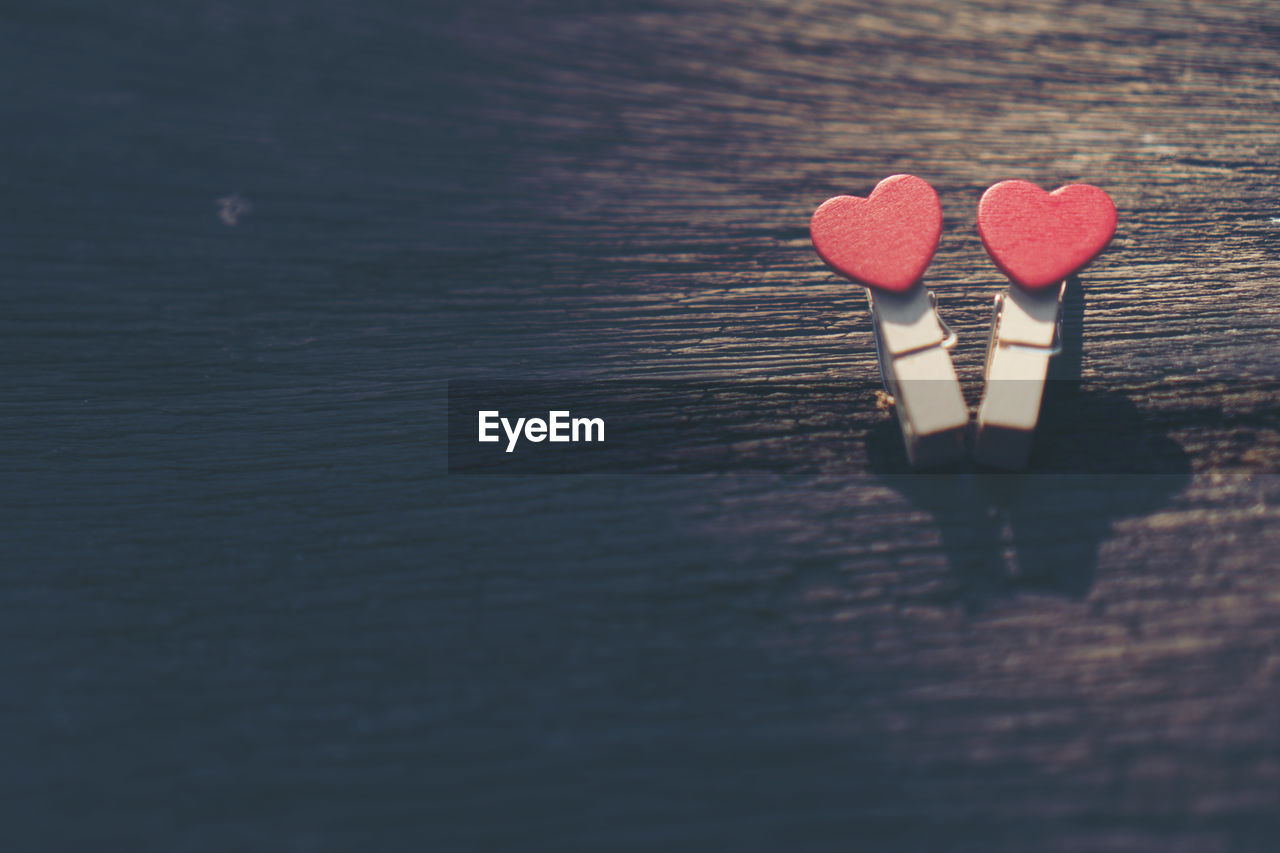 Close-up of red heart shapes on clothespins at table