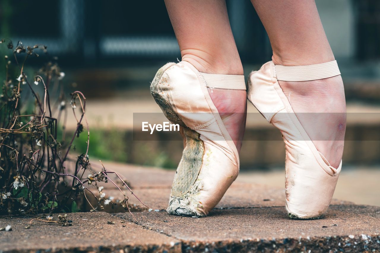 Low section of ballet dancer tiptoeing on footpath