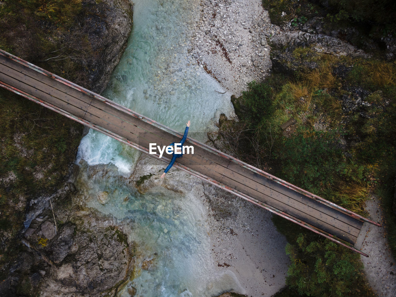 Austria, lower austria, annaberg, drone view of female hiker standing with raised arms on bridge stretching over otscherbach river