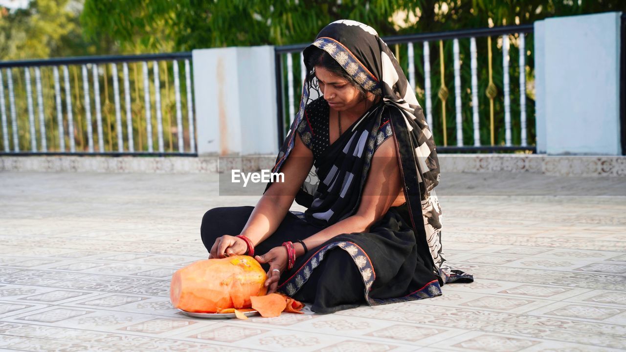 Indian woman cutting a fresh papaya. peeling the skin of ripe papaya with a knife