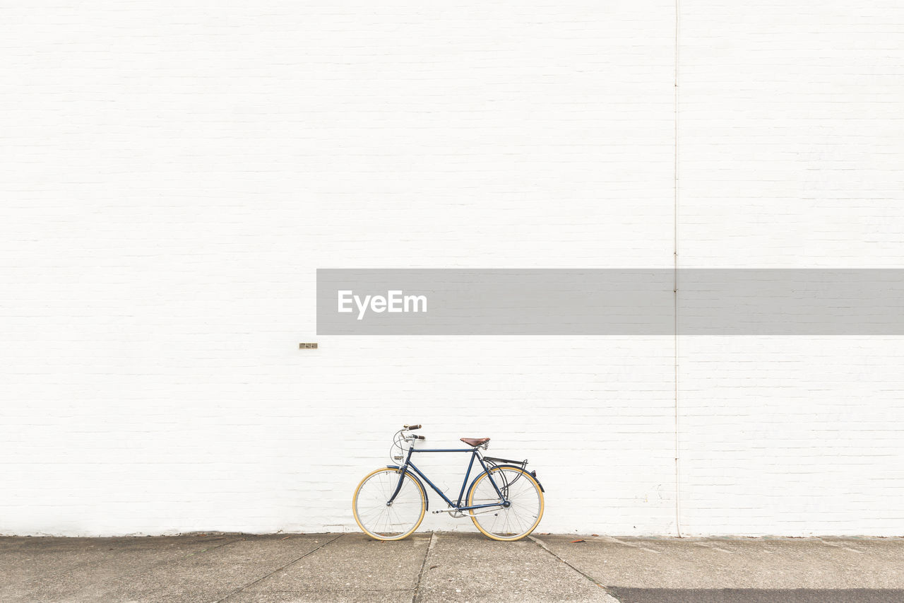 Bicycle on street against white wall