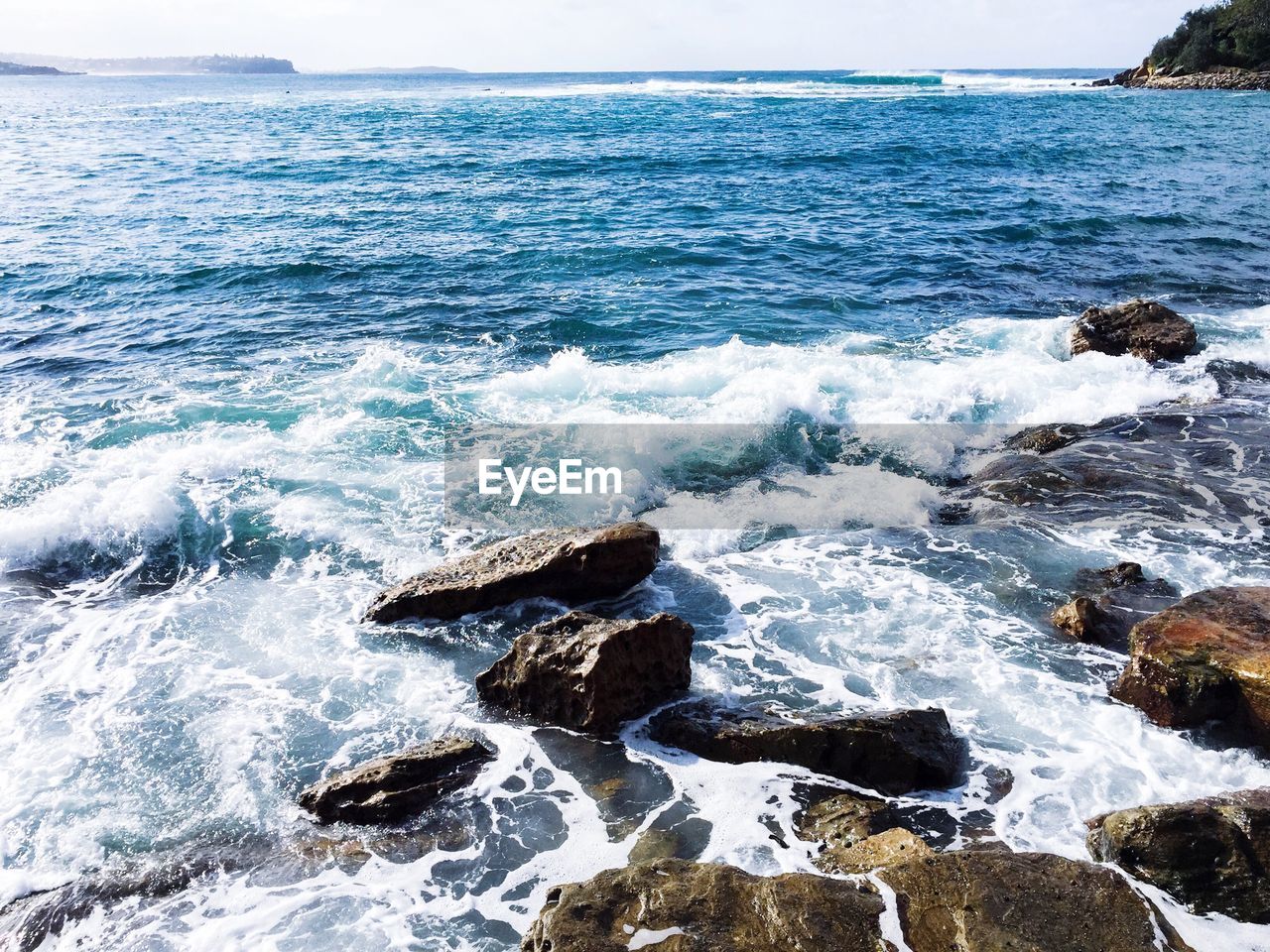 Waves splashing on shore against sky