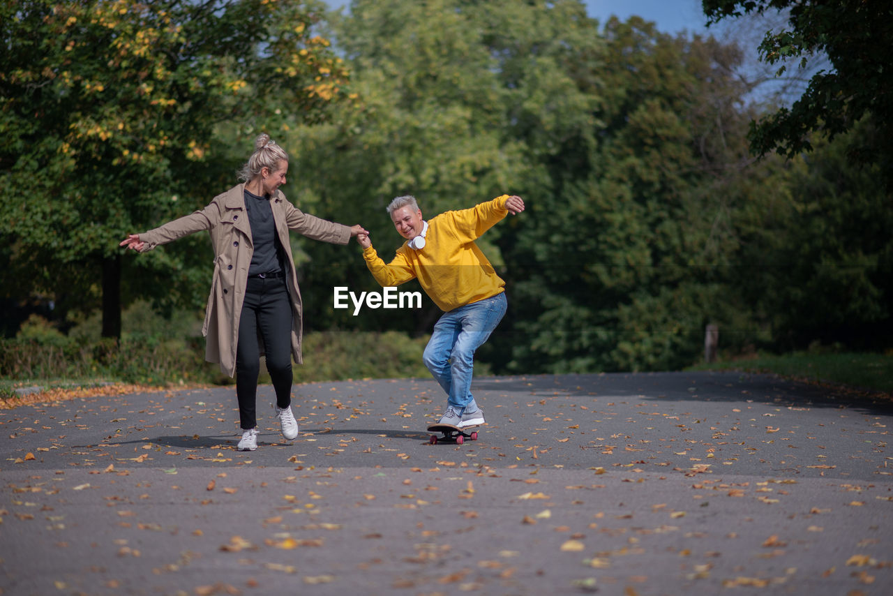 A couple rides a skateboard