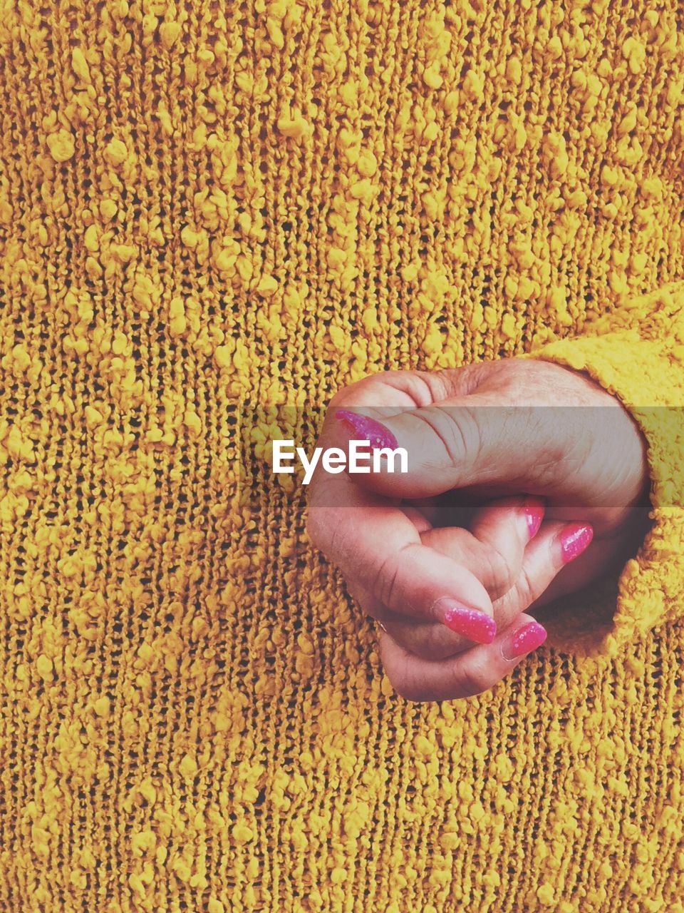 CLOSE-UP OF HAND ON RUG WITH YELLOW LEAF