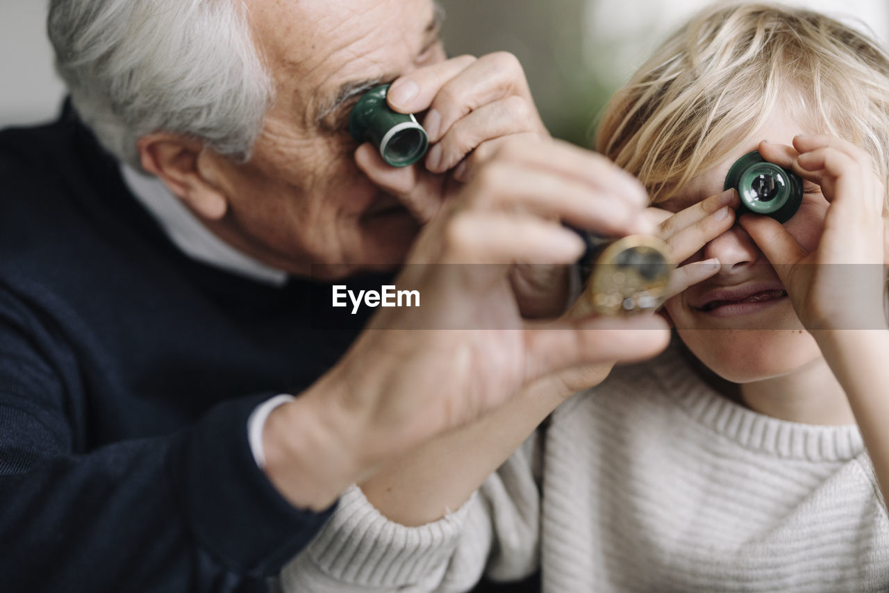 Watchmaker and his grandson examining watch together