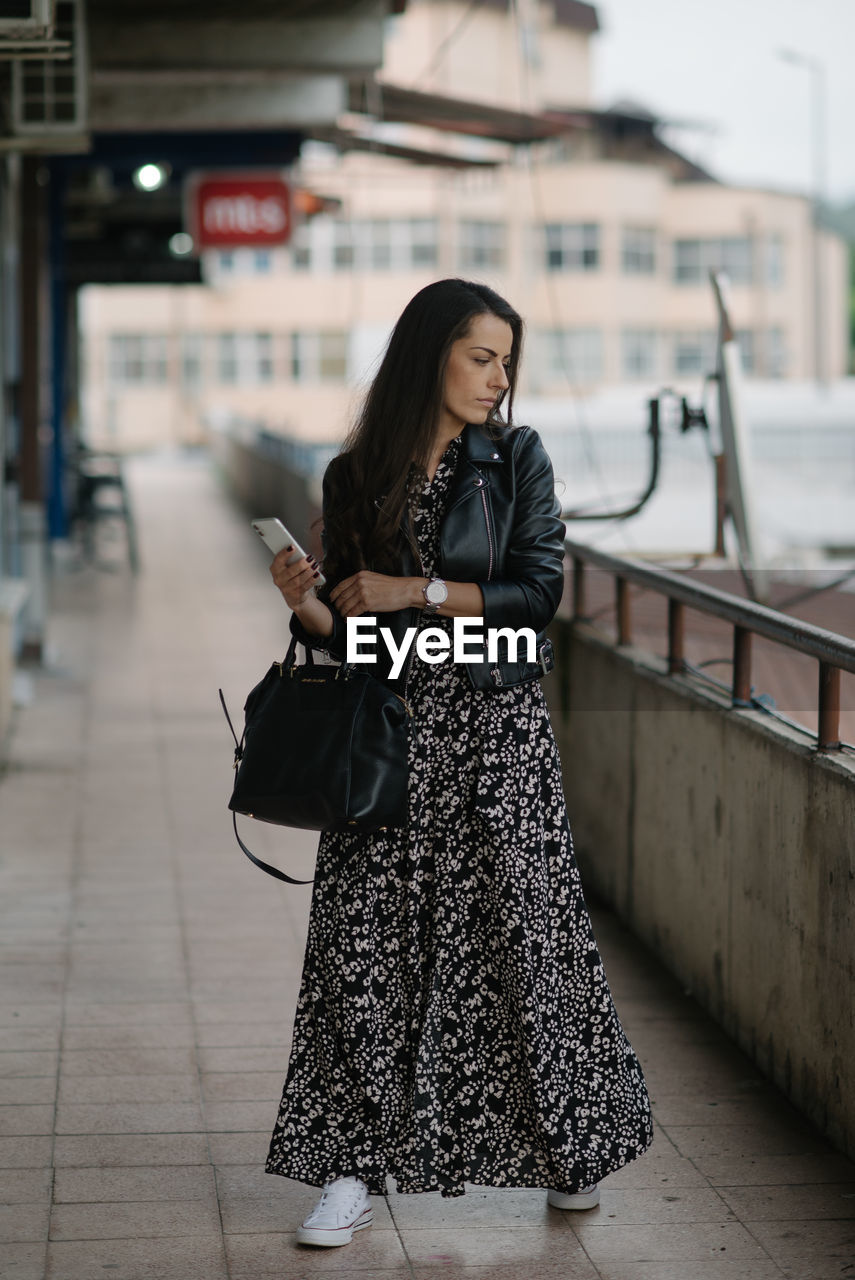 Attractive young lady with dress and leather jacket is posing.