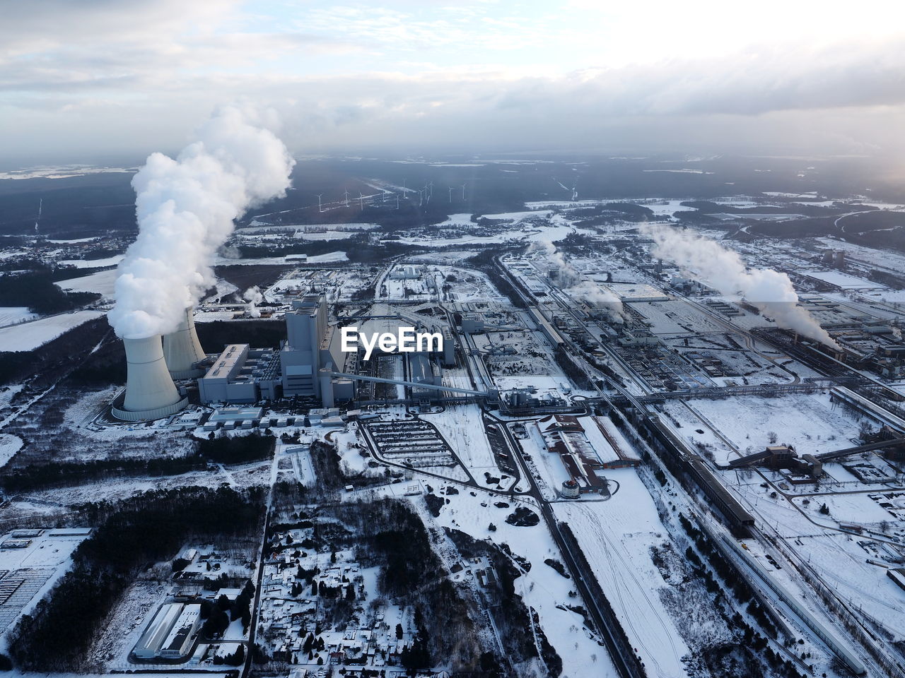 Aerial view of frozen lake against sky during winter with coal-fire power station