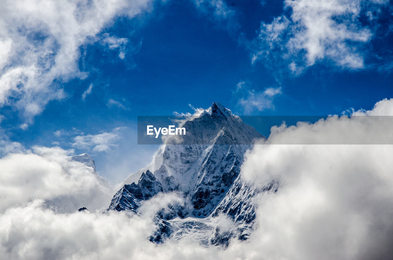 Clouds at snow covered mountain peak