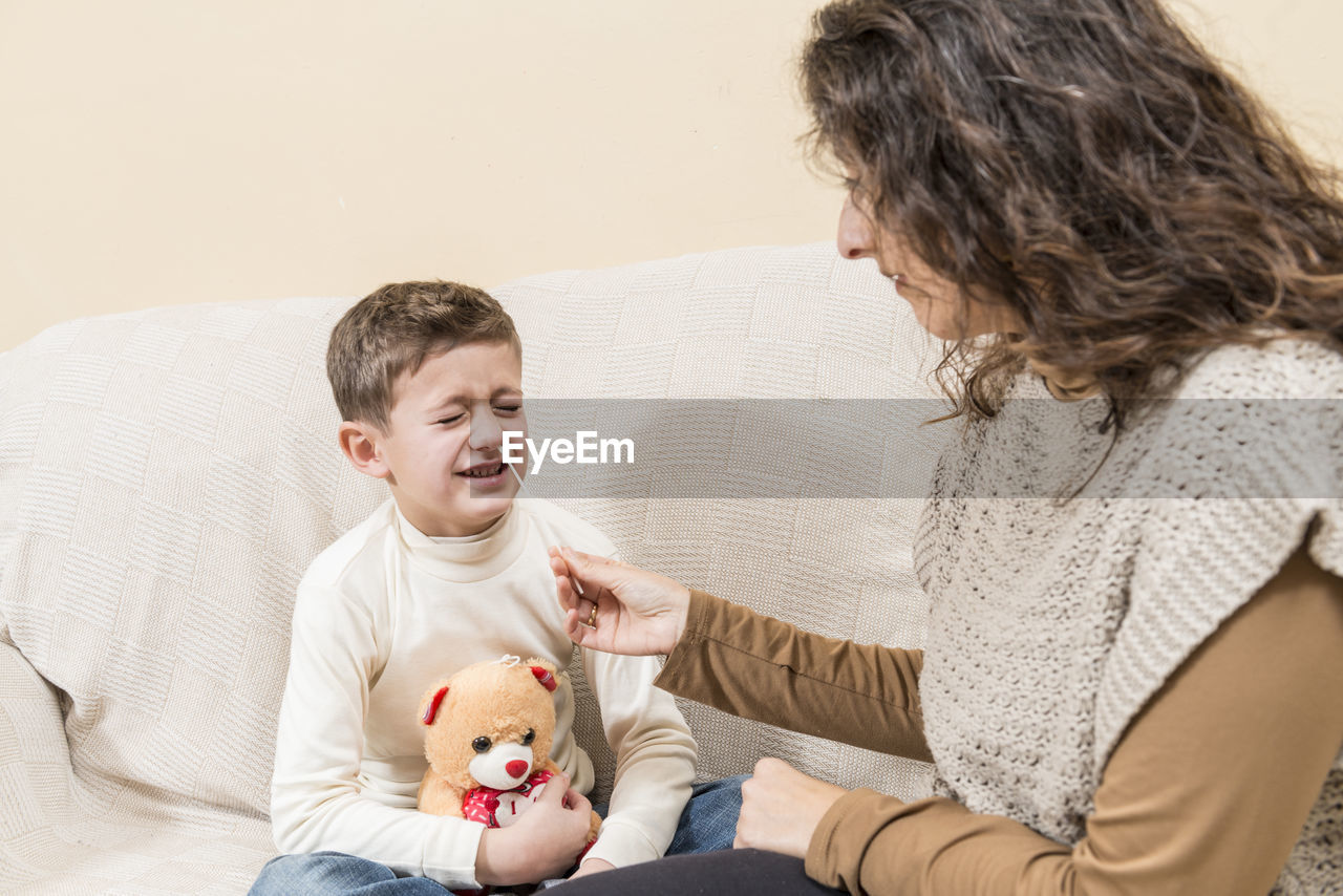 mother and daughter playing with stuffed toy on bed at home