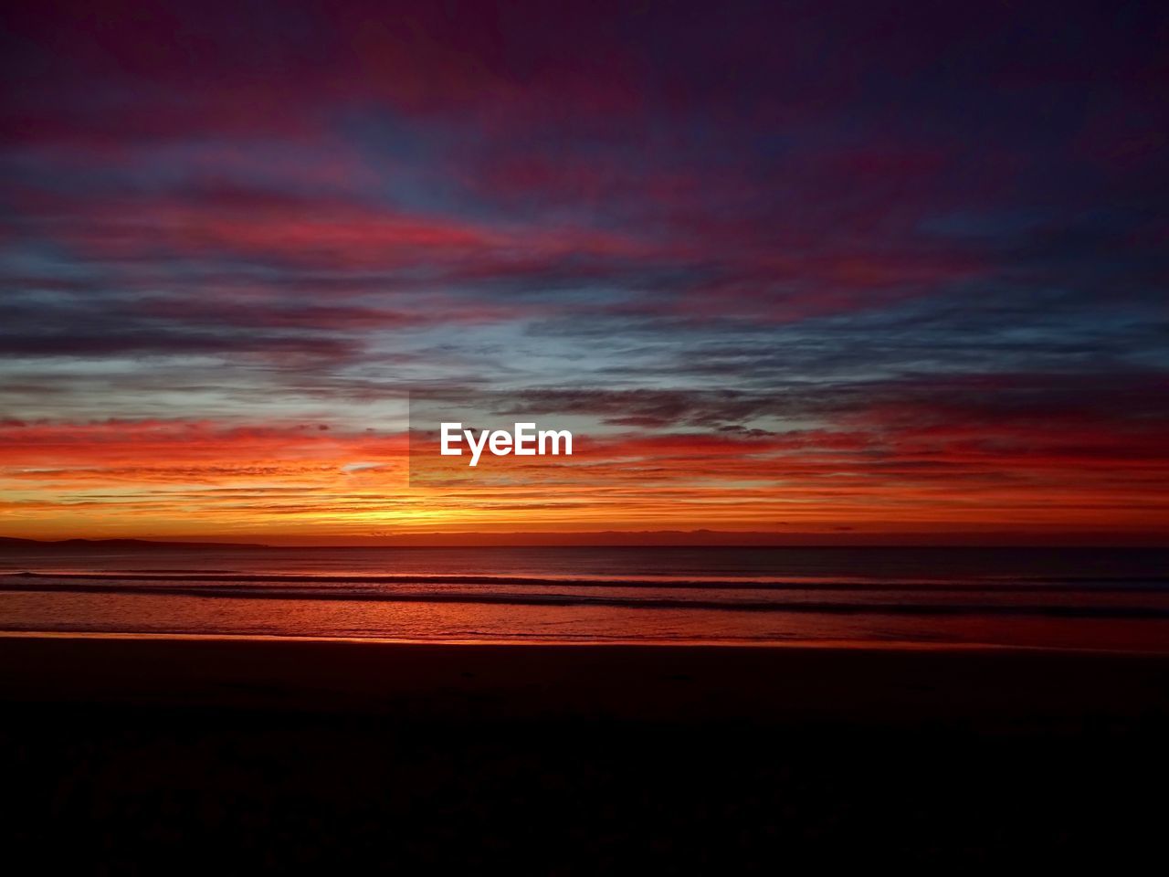 SCENIC VIEW OF BEACH AGAINST ORANGE SKY