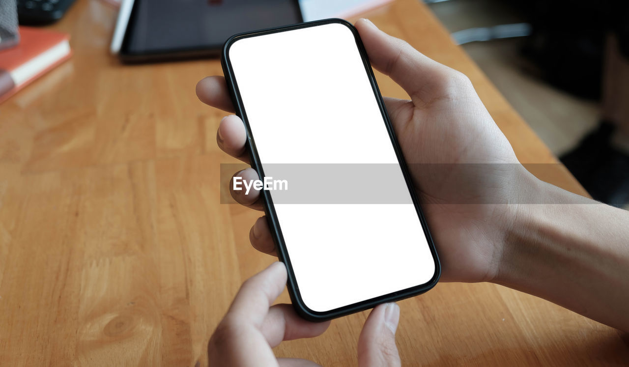 Cropped view of young woman holding smartphone with blank screen area for your internet.