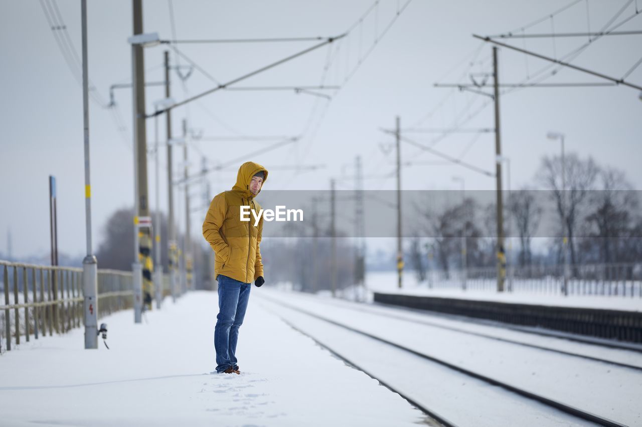 Snowy railroad station during frosty day. man standing on platform and waiting for delayed train.