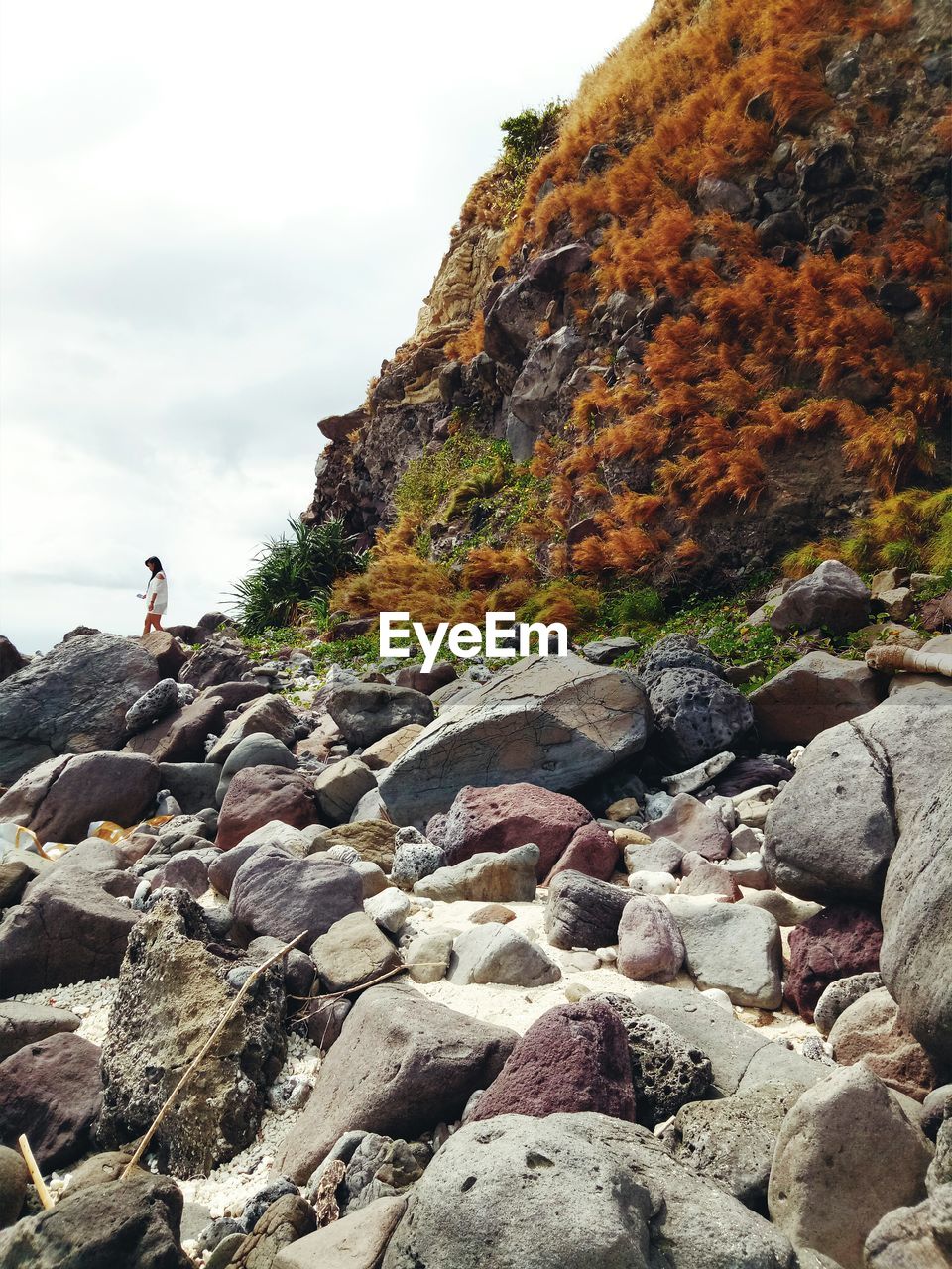 Side view of woman on rocks against sky