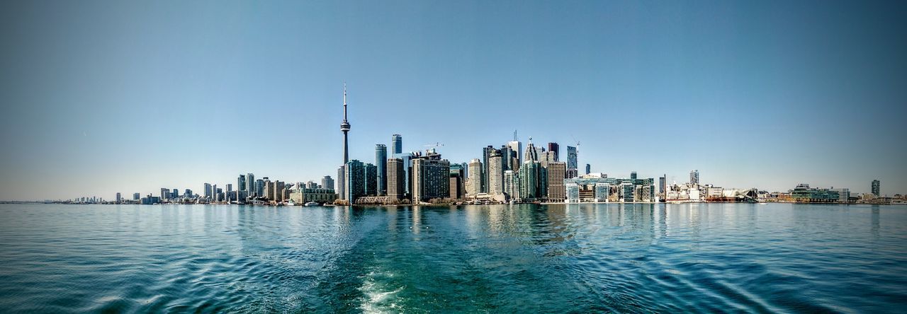 Panoramic shot of sea by cn tower and city against clear blue sky